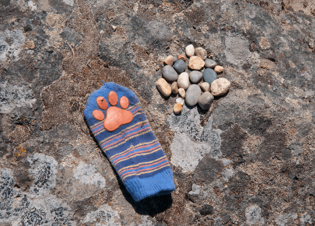 small blue striped baby sock lying on basalt with collection of small rocks next to it